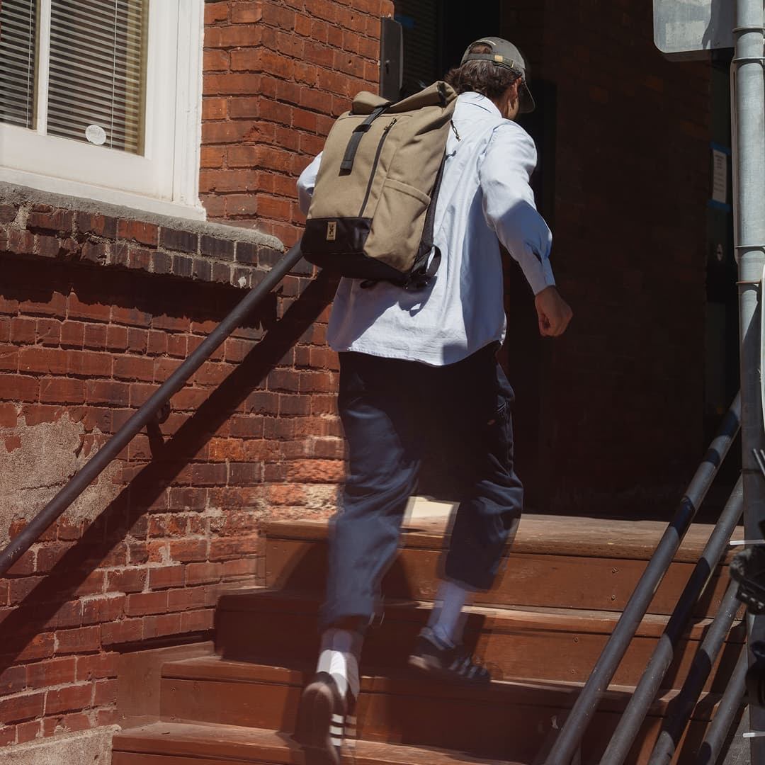A guy running up the steps to work in an Initiate 26L Pack