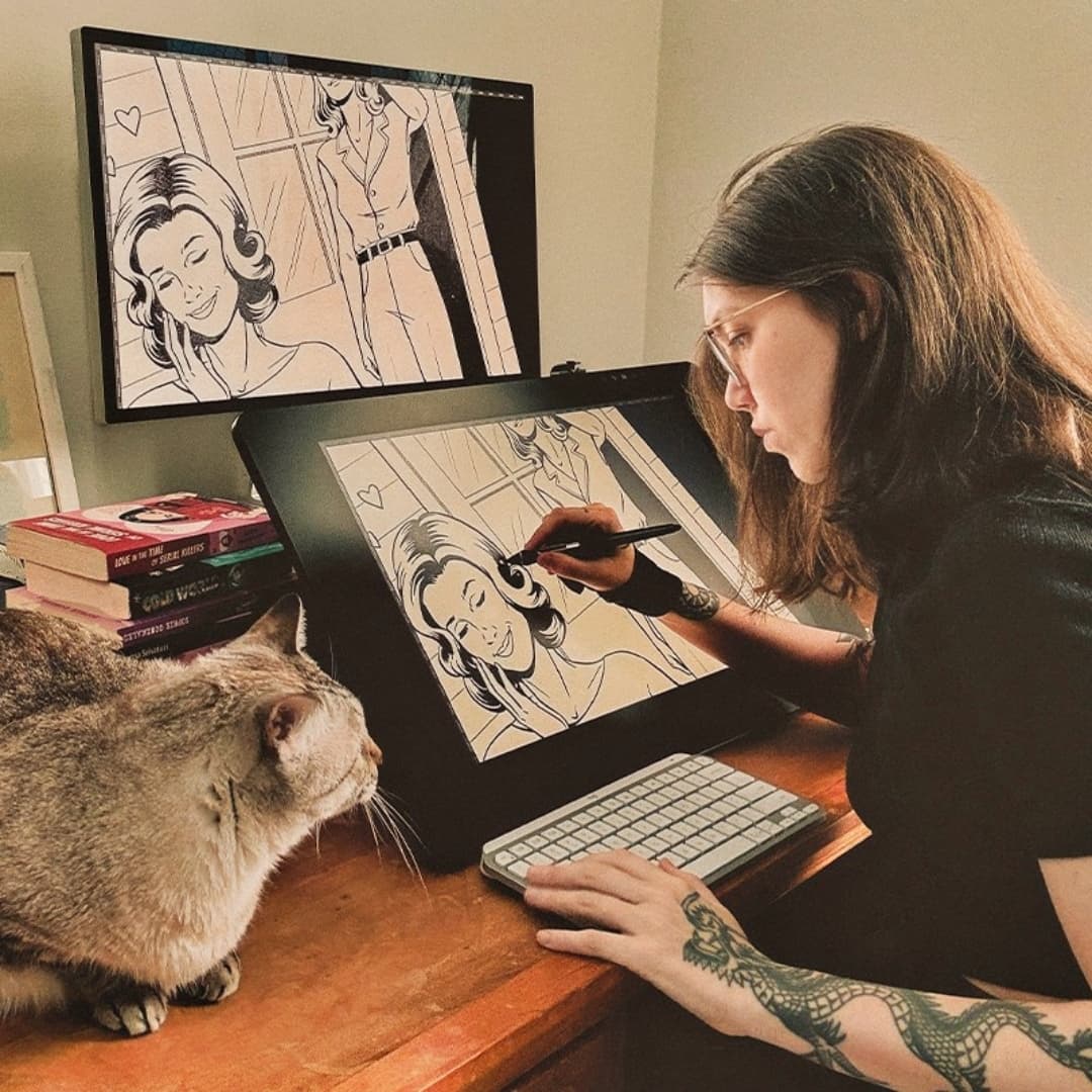 J. Prince drawing while her cat watches