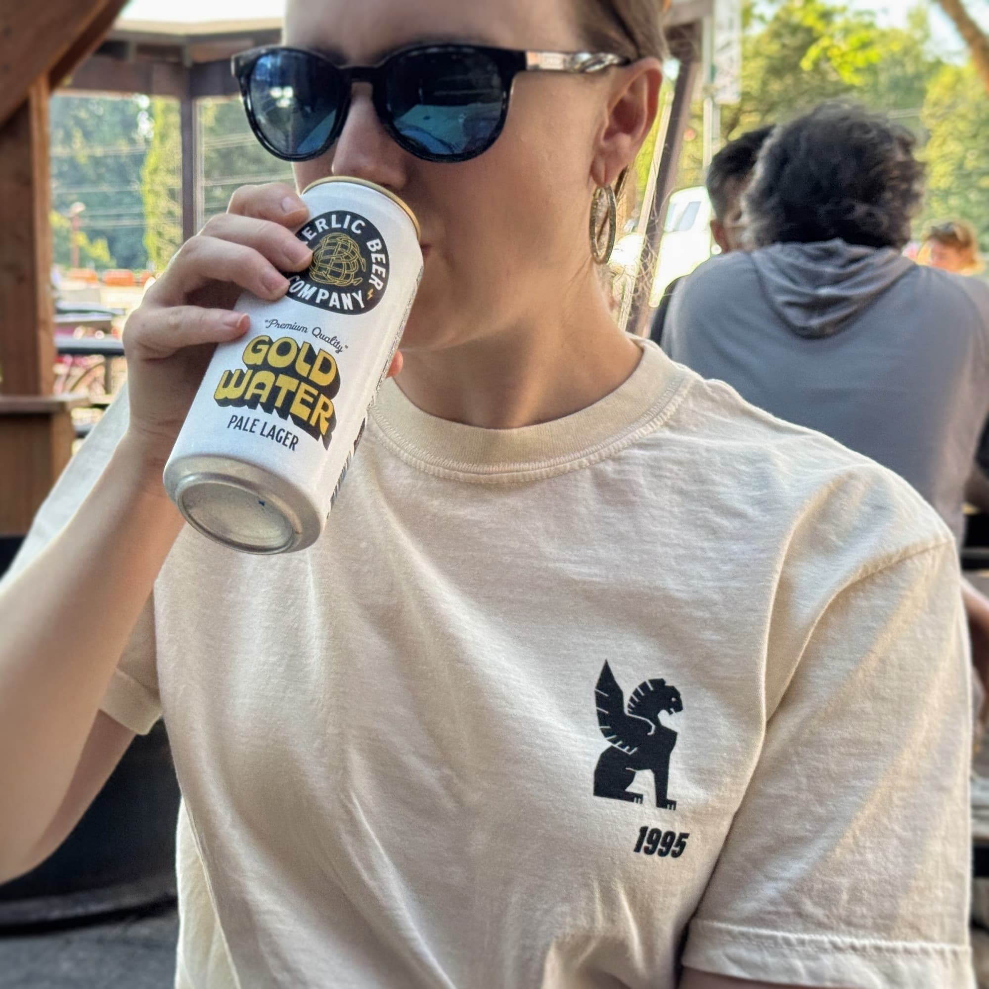 Person drinking from a Gold Water beer can outdoors