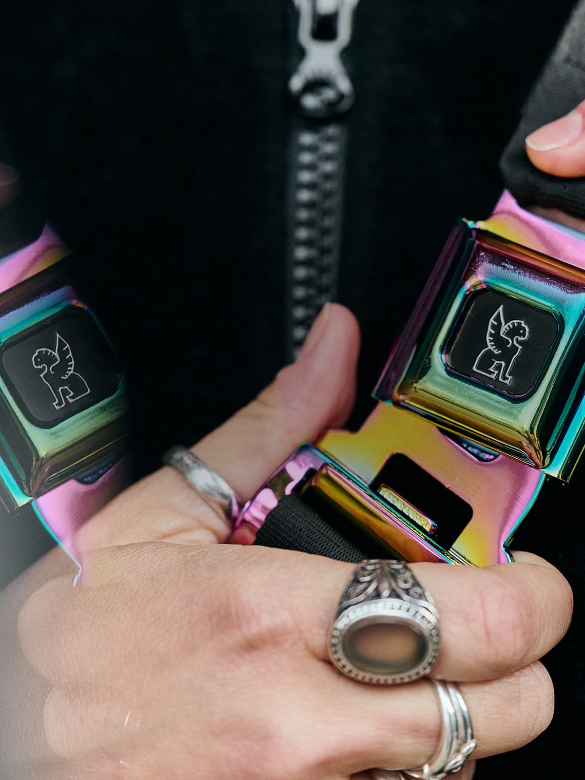 Hand grasping an iconic Chrome buckle in rainbow reflective