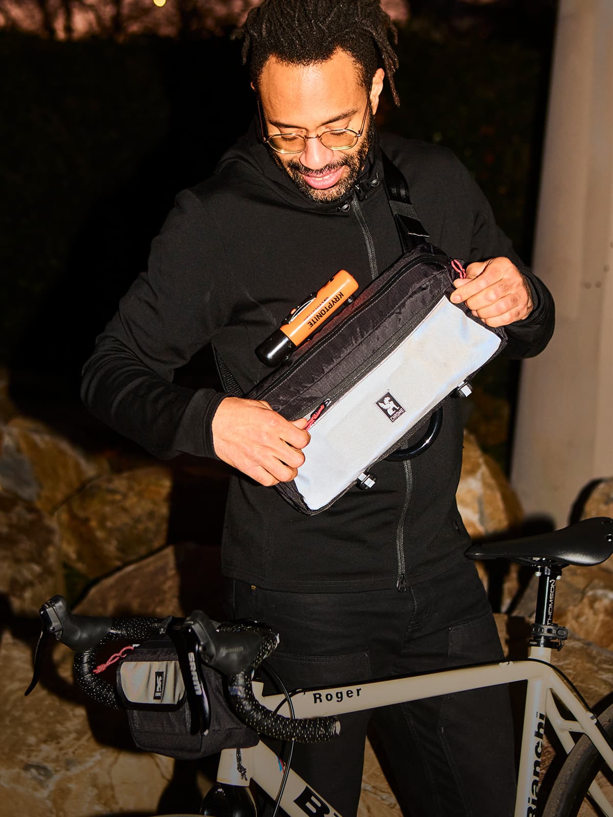 A guy standing by his bike with the Kadet in BXRF reflective unzipping the pocket