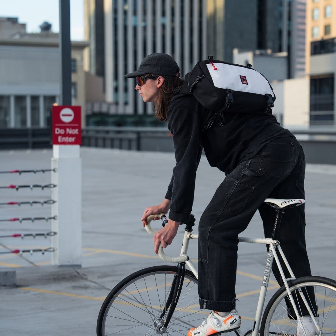 A guy riding his bike wearing the new Kadet Max 15L in classic colors