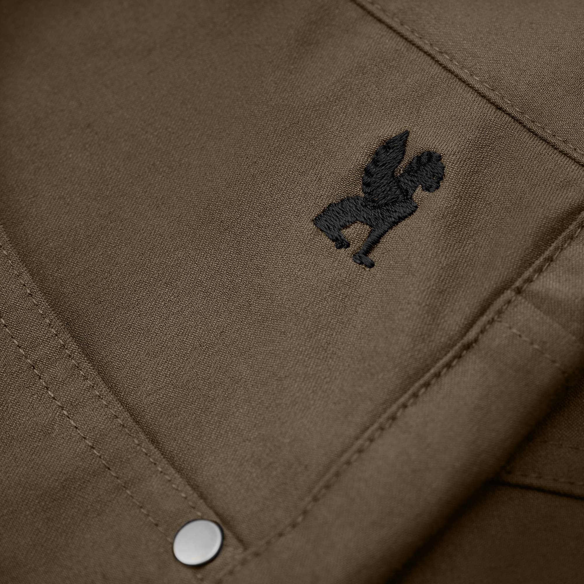 Zoomed in logo on the Madrona Men's shorts in brown #color_stone grey