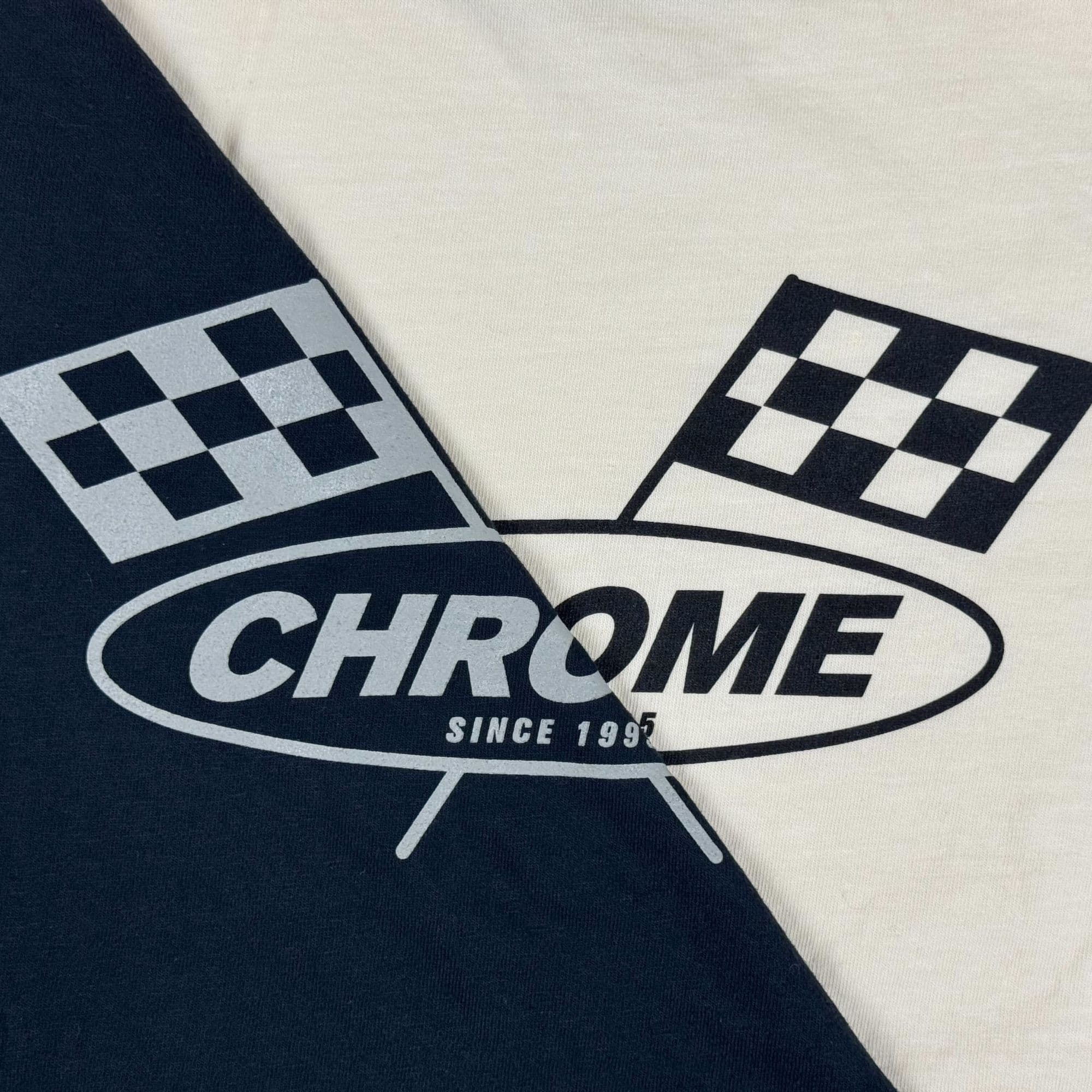 Close-up of a shirt with a 'Chrome' logo featuring checkered flags on a black and white background.