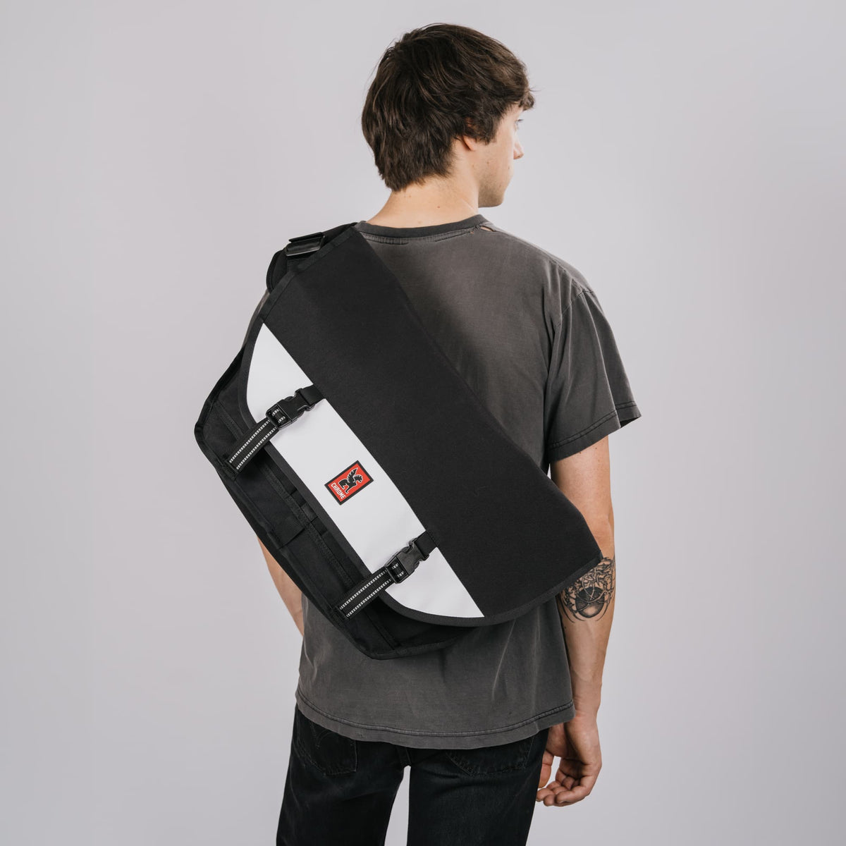 The Citizen 24L Messenger in new Classic Black White on the back of a guy #color_classic / black / white