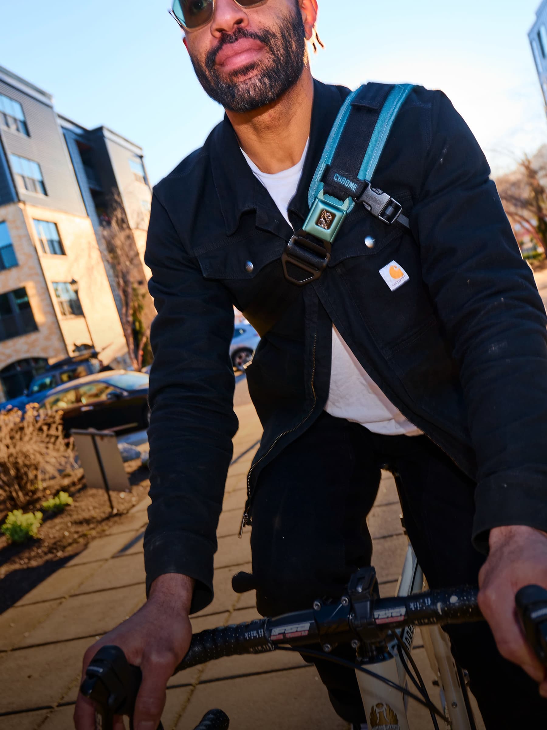 Man riding a bicycle on a sidewalk with a Kadet Max and buildings in the background