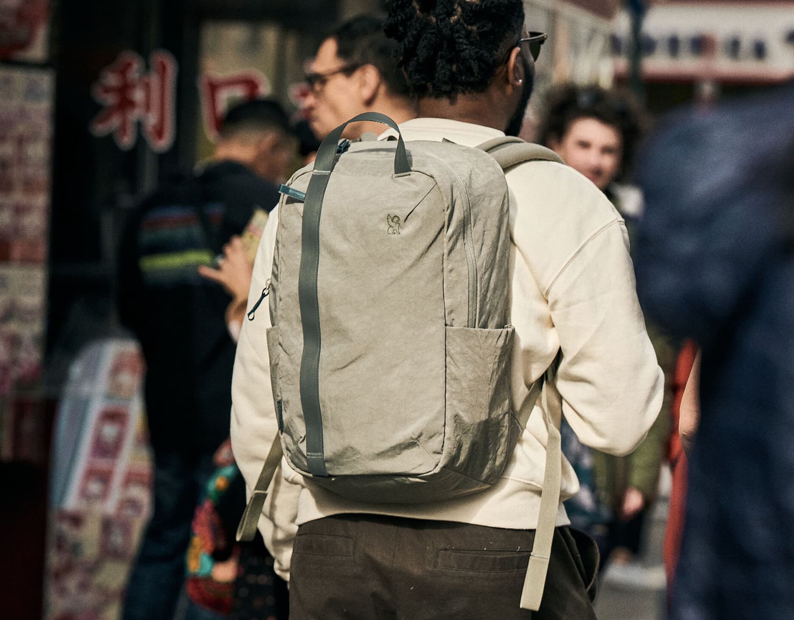 Man in a creme jacket wearing a district backpack