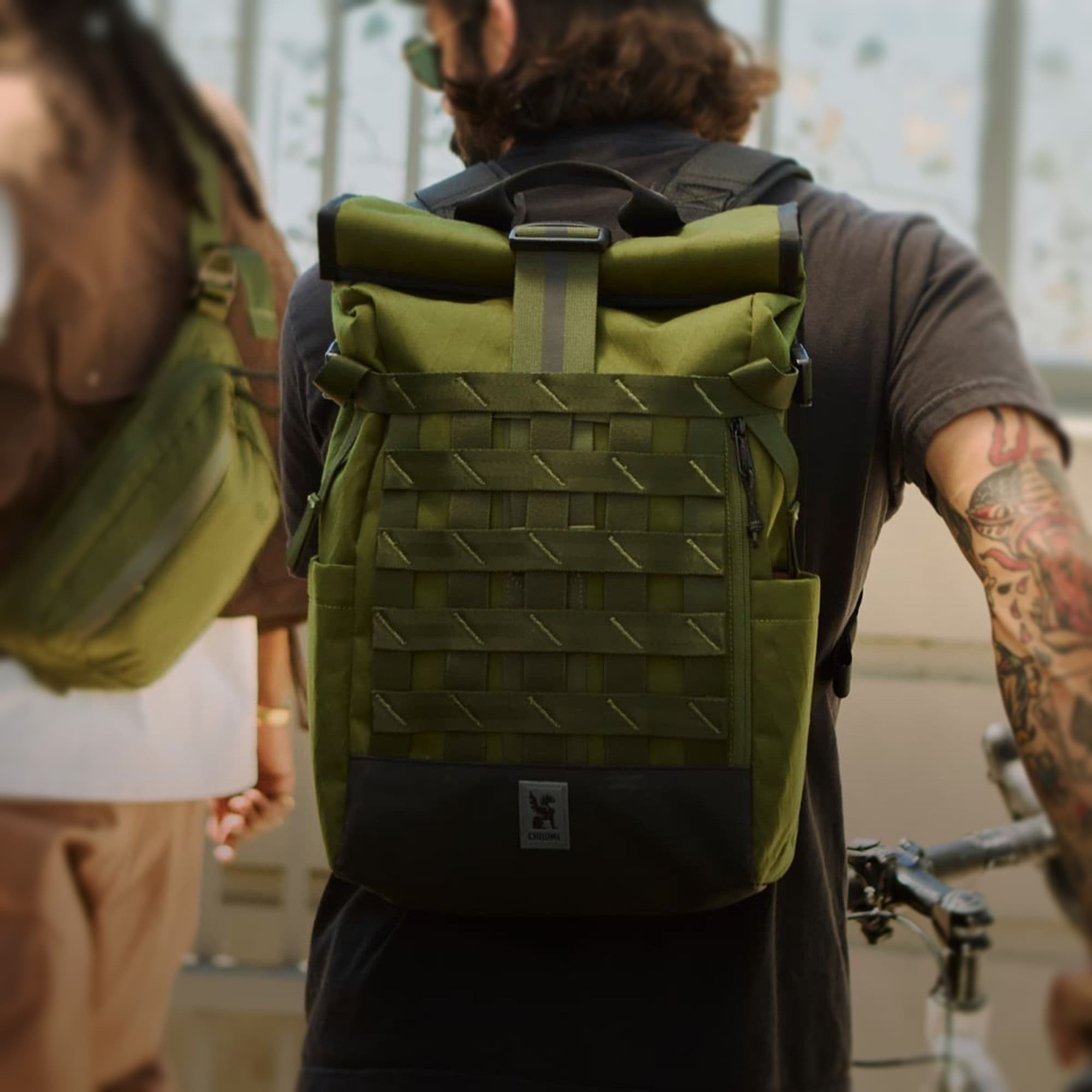 The Barrage 22L Pack in moss x on a guy walking his bike #color_moss x