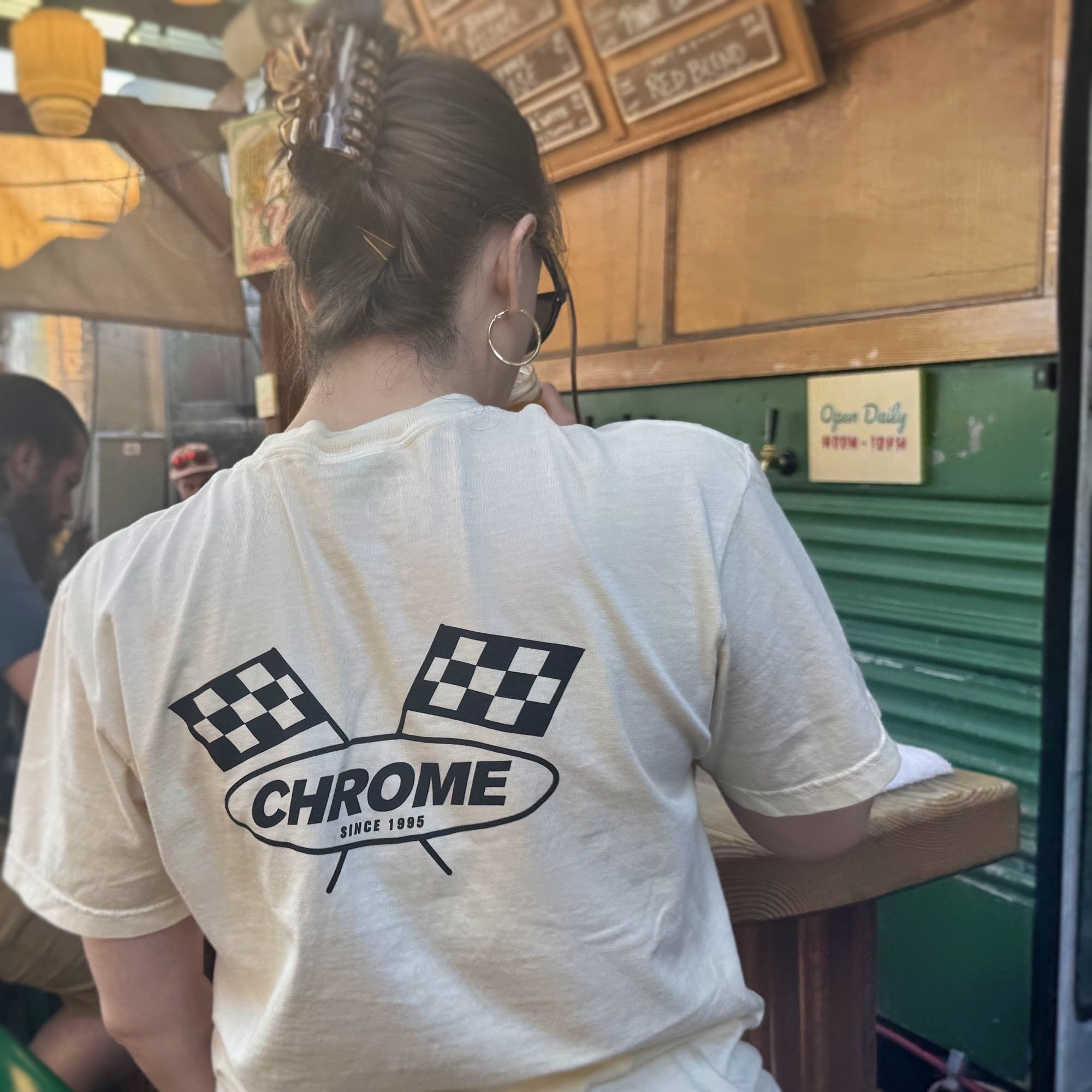 Person wearing a white t-shirt with 'Chrome' logo in an indoor setting
