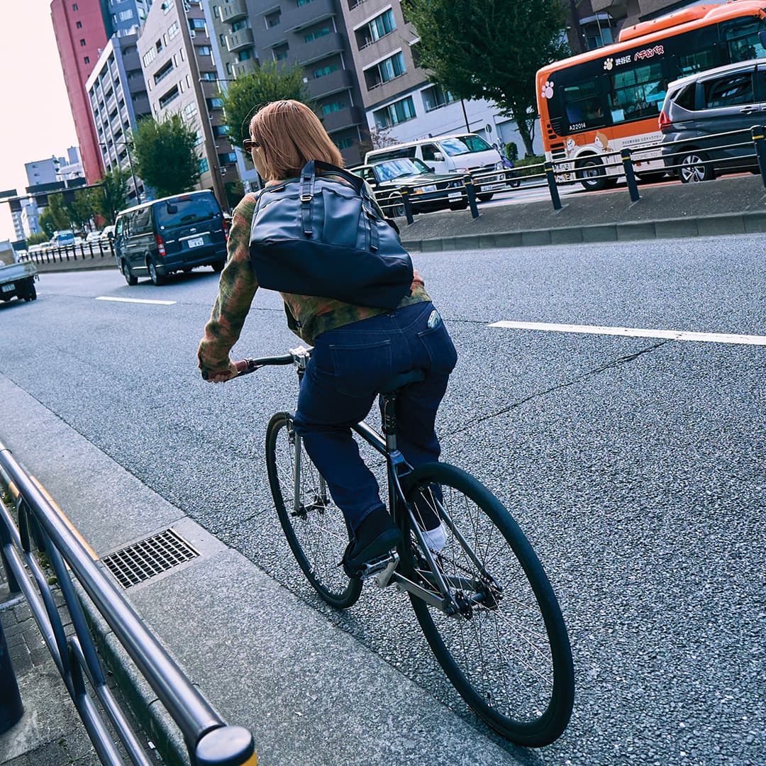 A woman riding a bike with the Japan designed Grocery 28L Tote