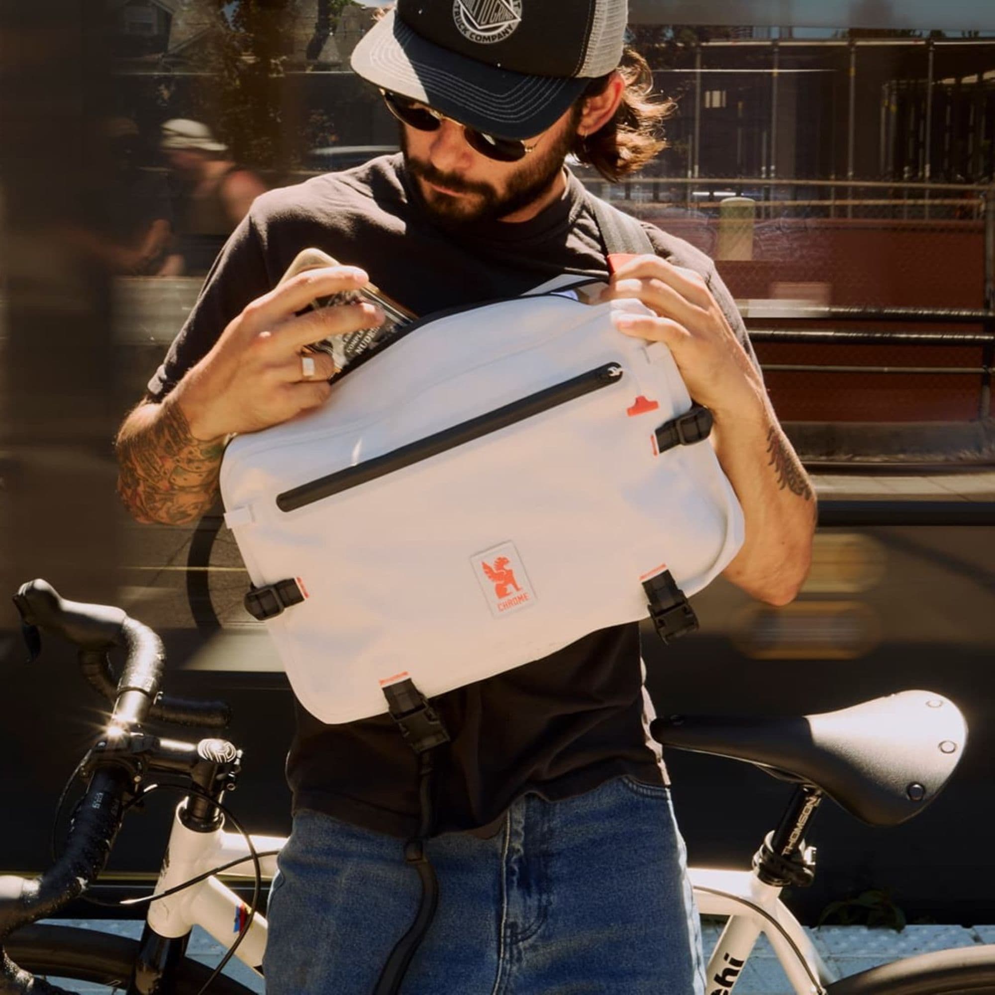 A guy putting his phone into the Kadet Max Waterproof commute sling #color_future white