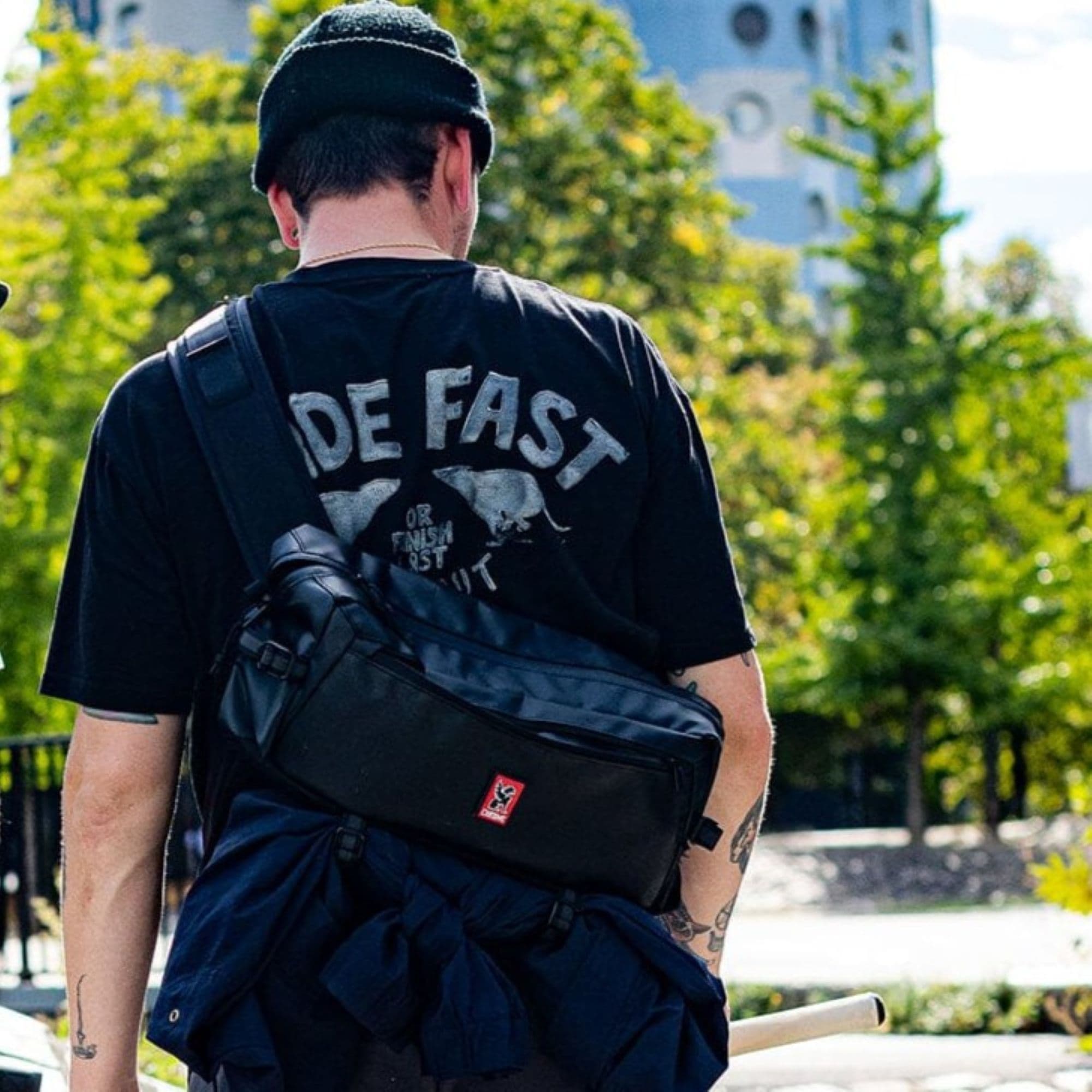 The Kadet 9L Sling in black tarp on a guy walking #color_black tarp