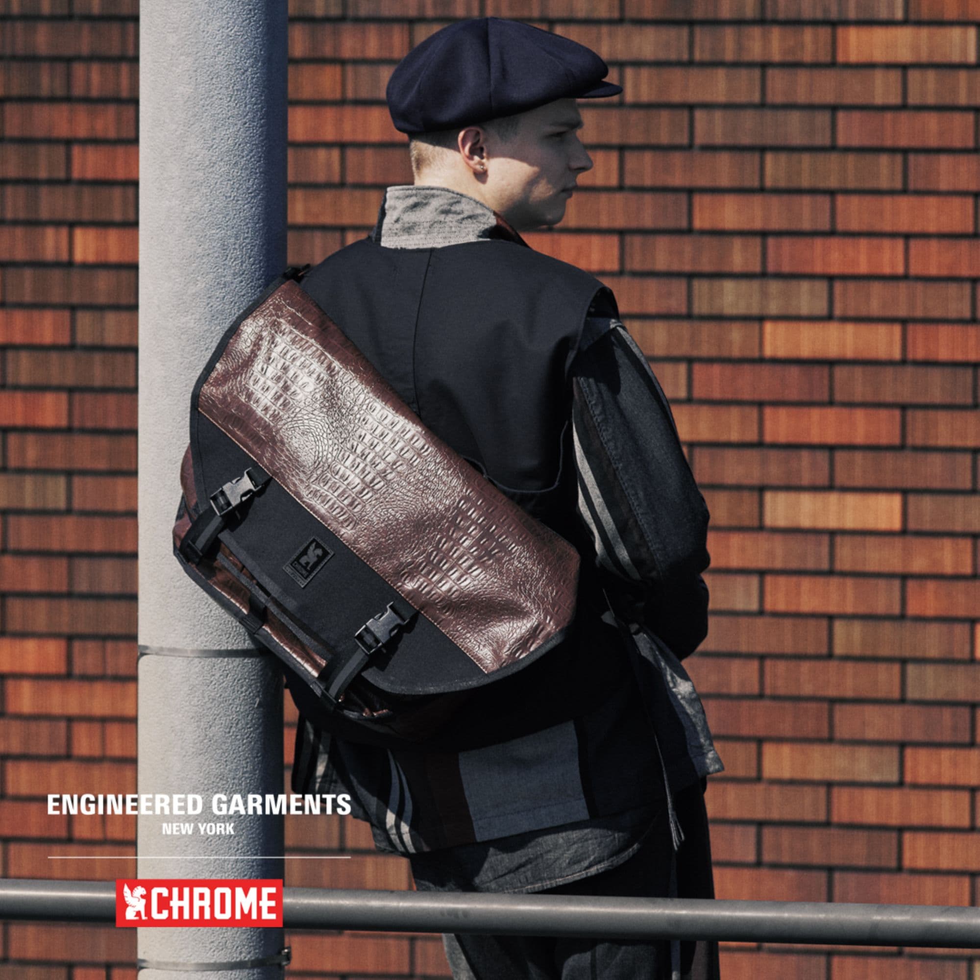 Person wearing a EG edition Citizen 24L Messenger against a brick wall #color_croco / dark brown