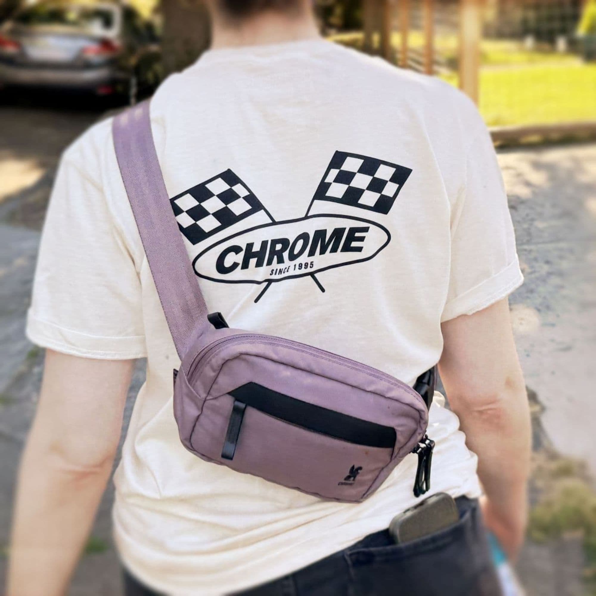 Person wearing a white t-shirt with a 'Chrome' logo and a mauve crossbody Sabin Sling.