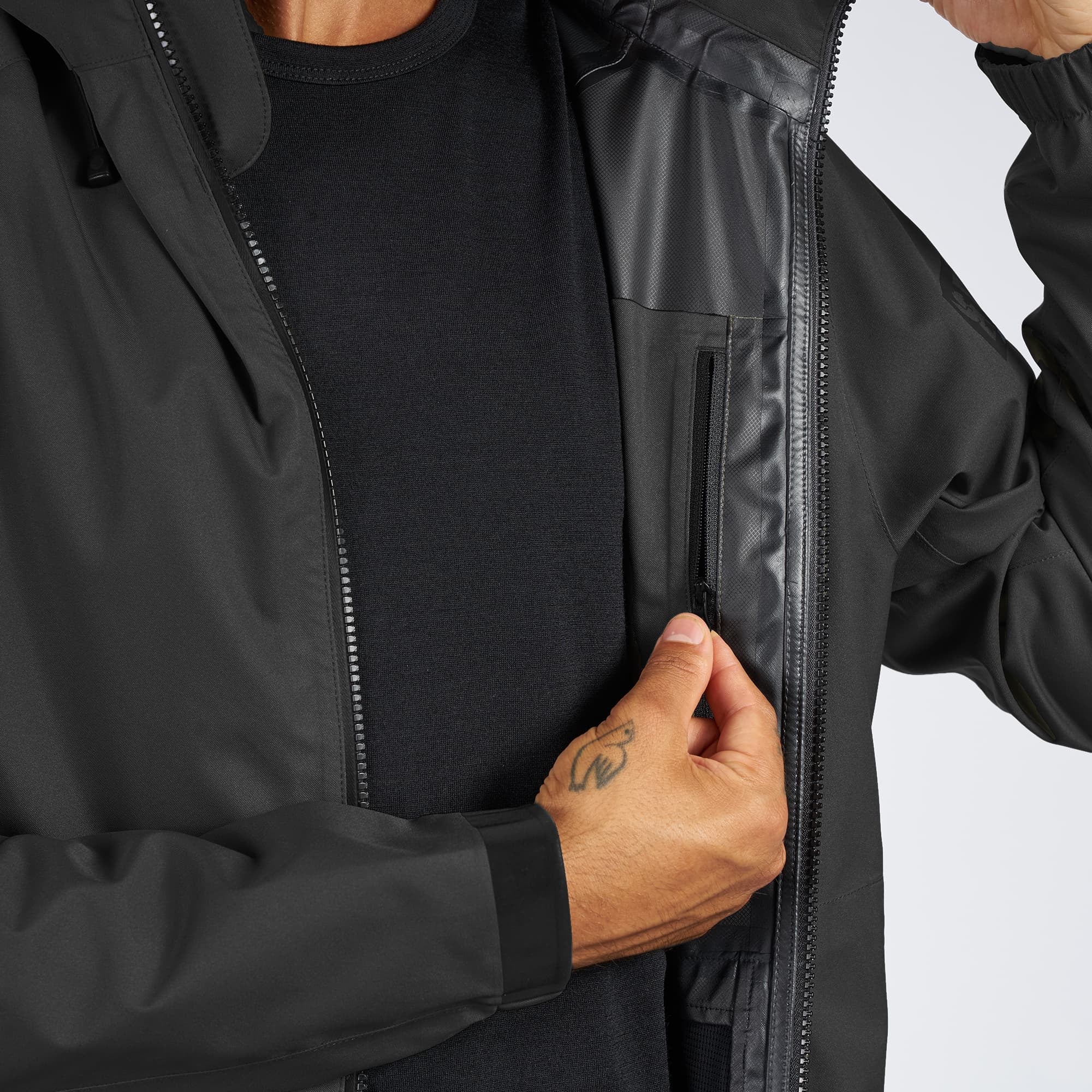 Waterproof rain jacket in black worn by a man inside zipper pocket