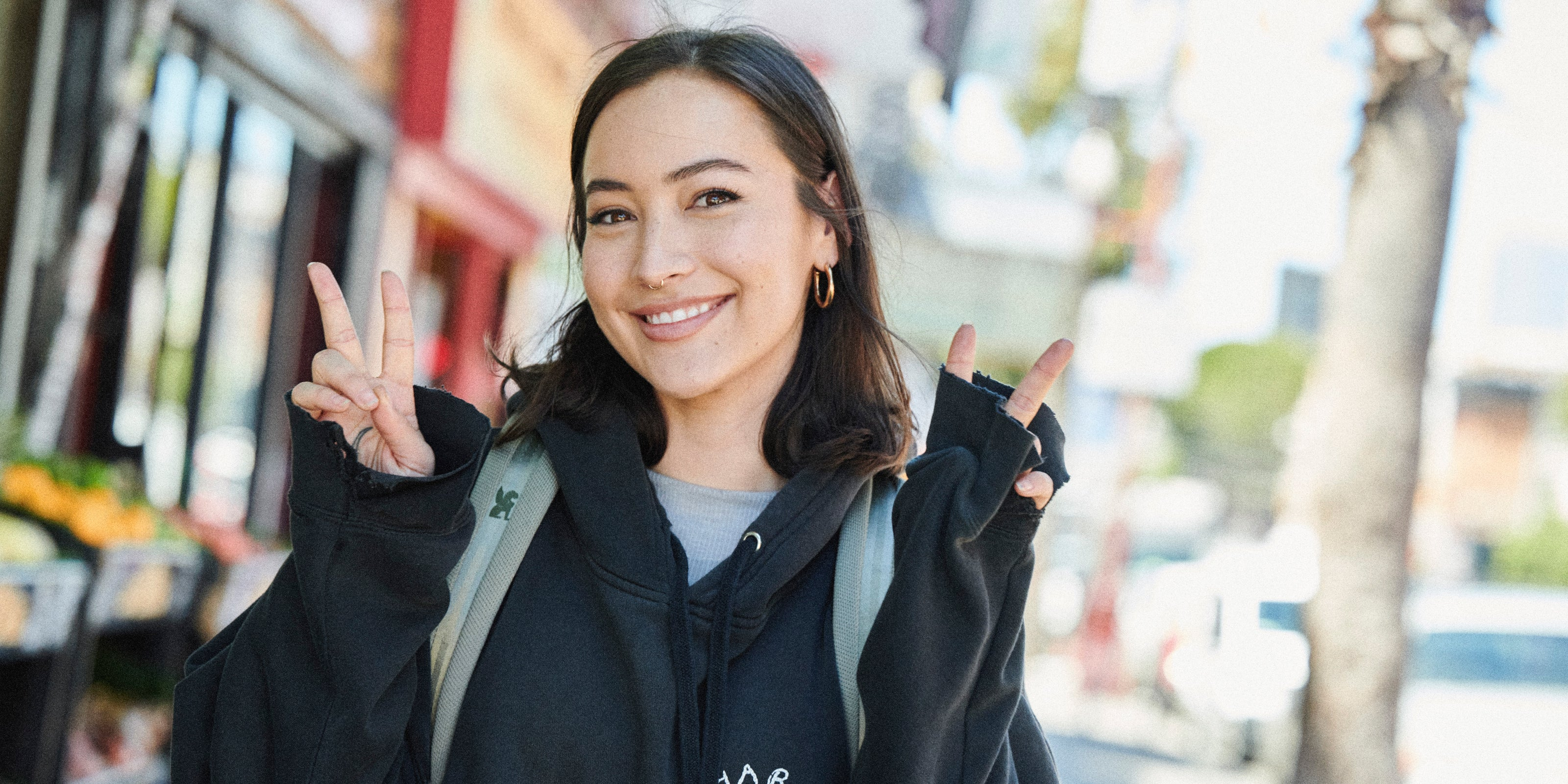 Woman flashing the peace sign wearing the Camden backpack