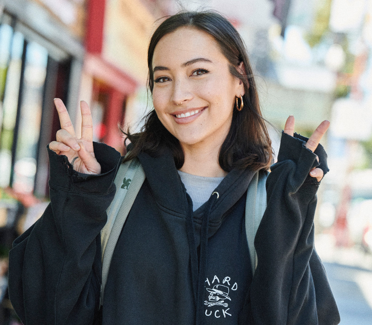 Woman wearing the Camden pack showing the peace sign