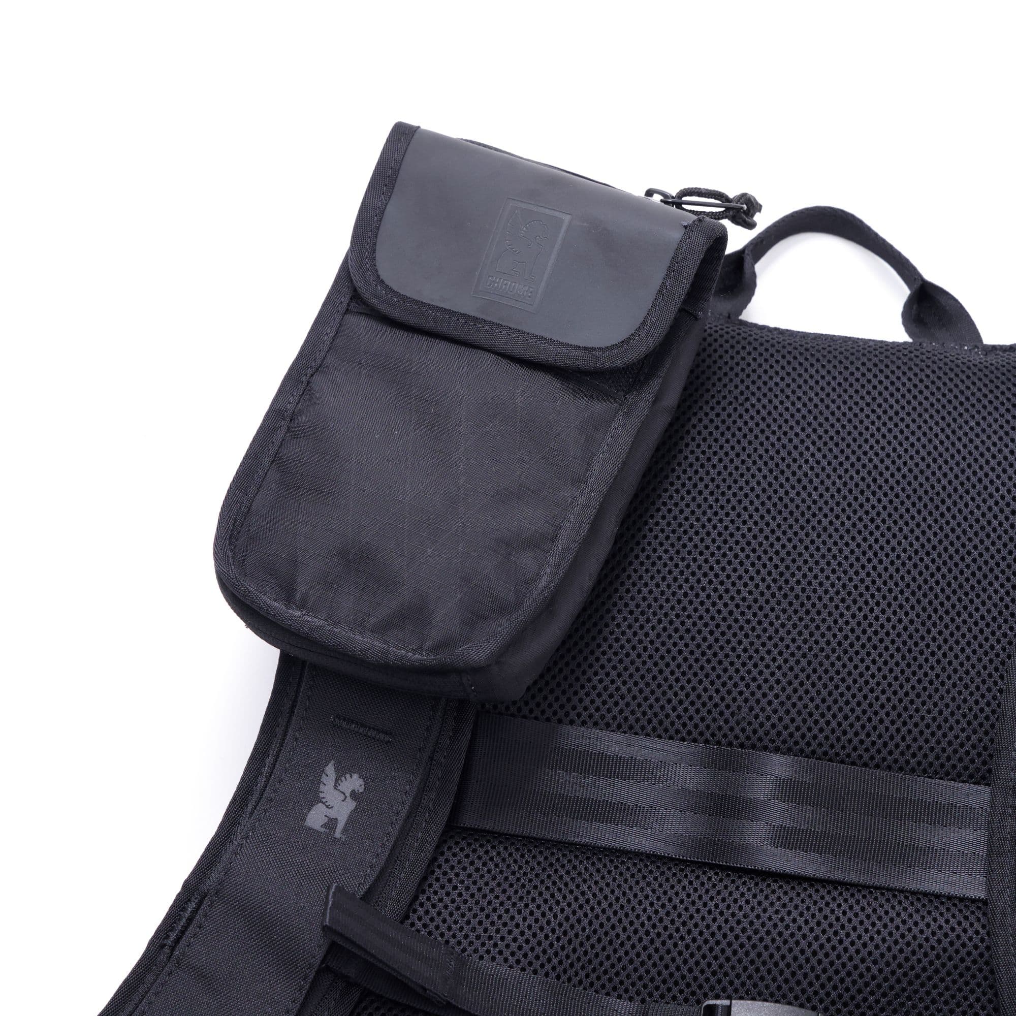 The Travel Tech Pouch in black mounted on a backpack strap