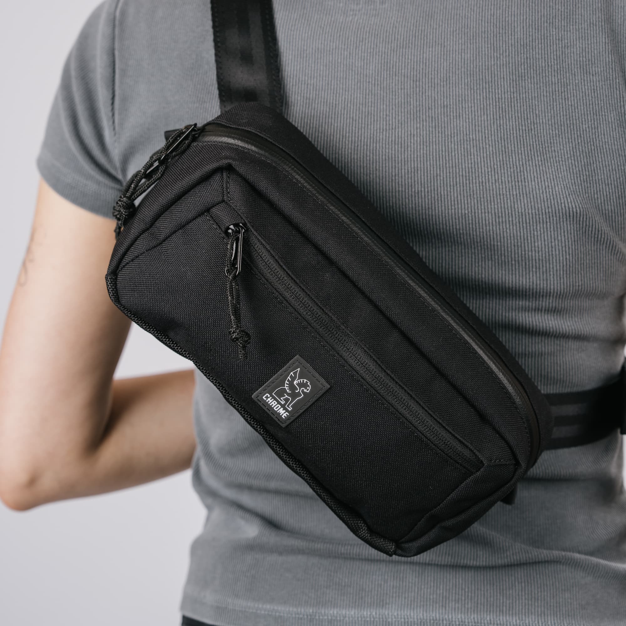 A woman wearing the new Micro Kadet Crossbody zoomed in to see the Chrome Logo.