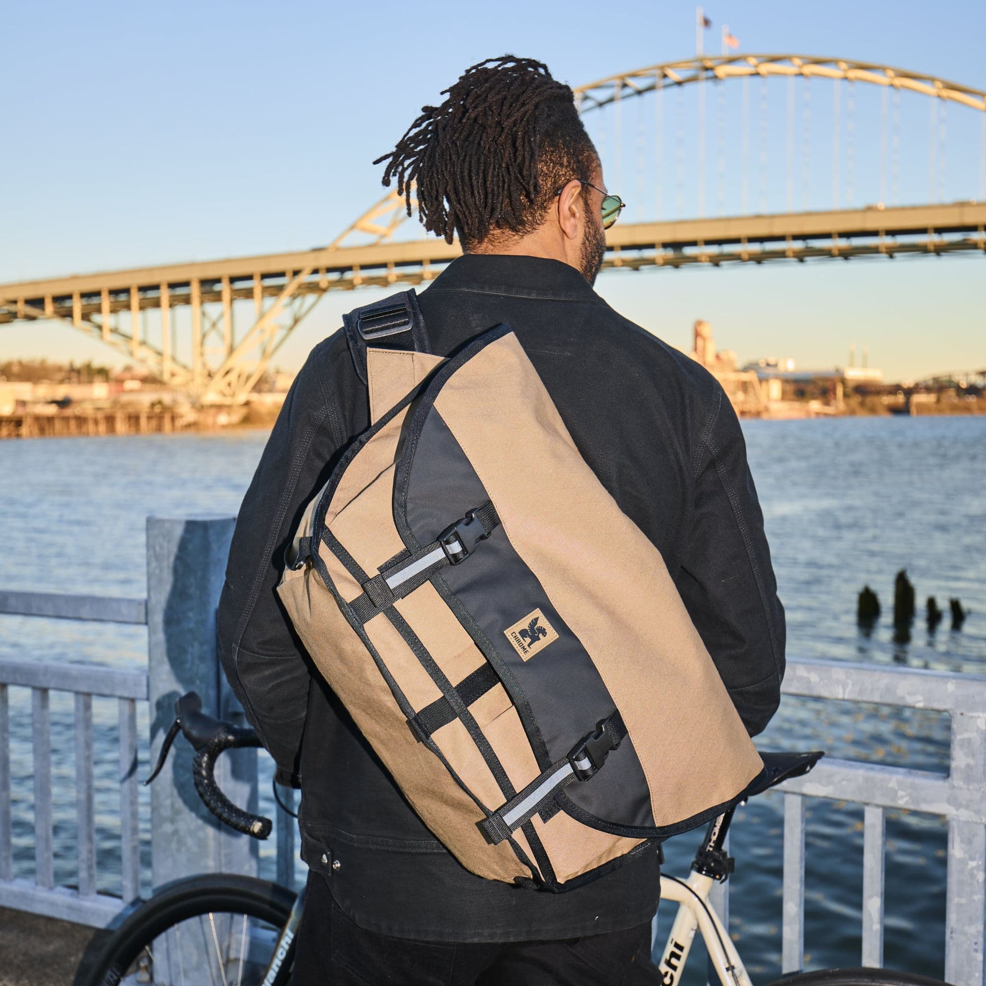 A person wearing a Citizen 24L Messenger in brown #color_coyote x