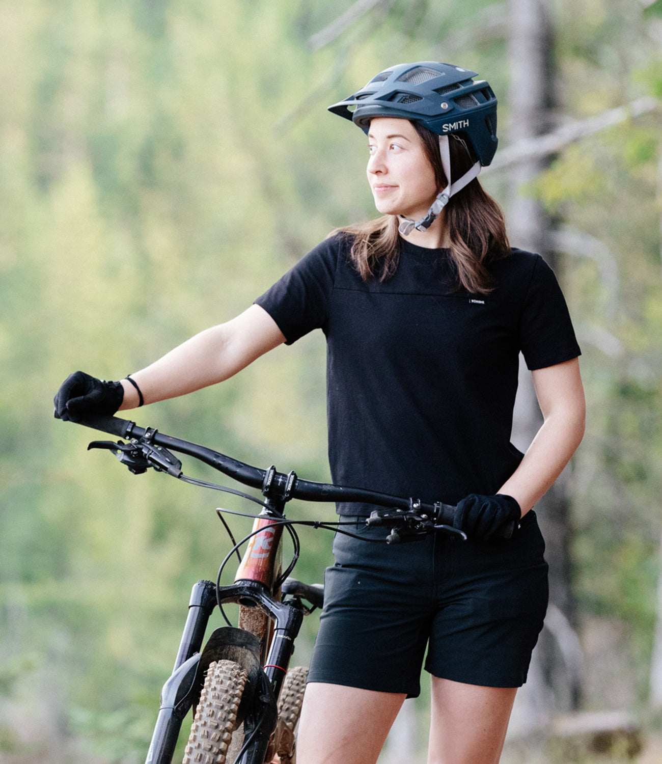 Women's Holman Tee in black worn by a woman riding a mountain bike mobile size image