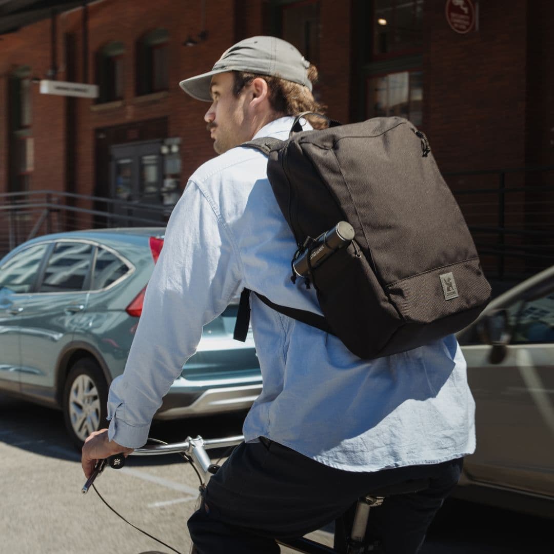 A man commuting by bike in the new Recruit 22L Pack in black