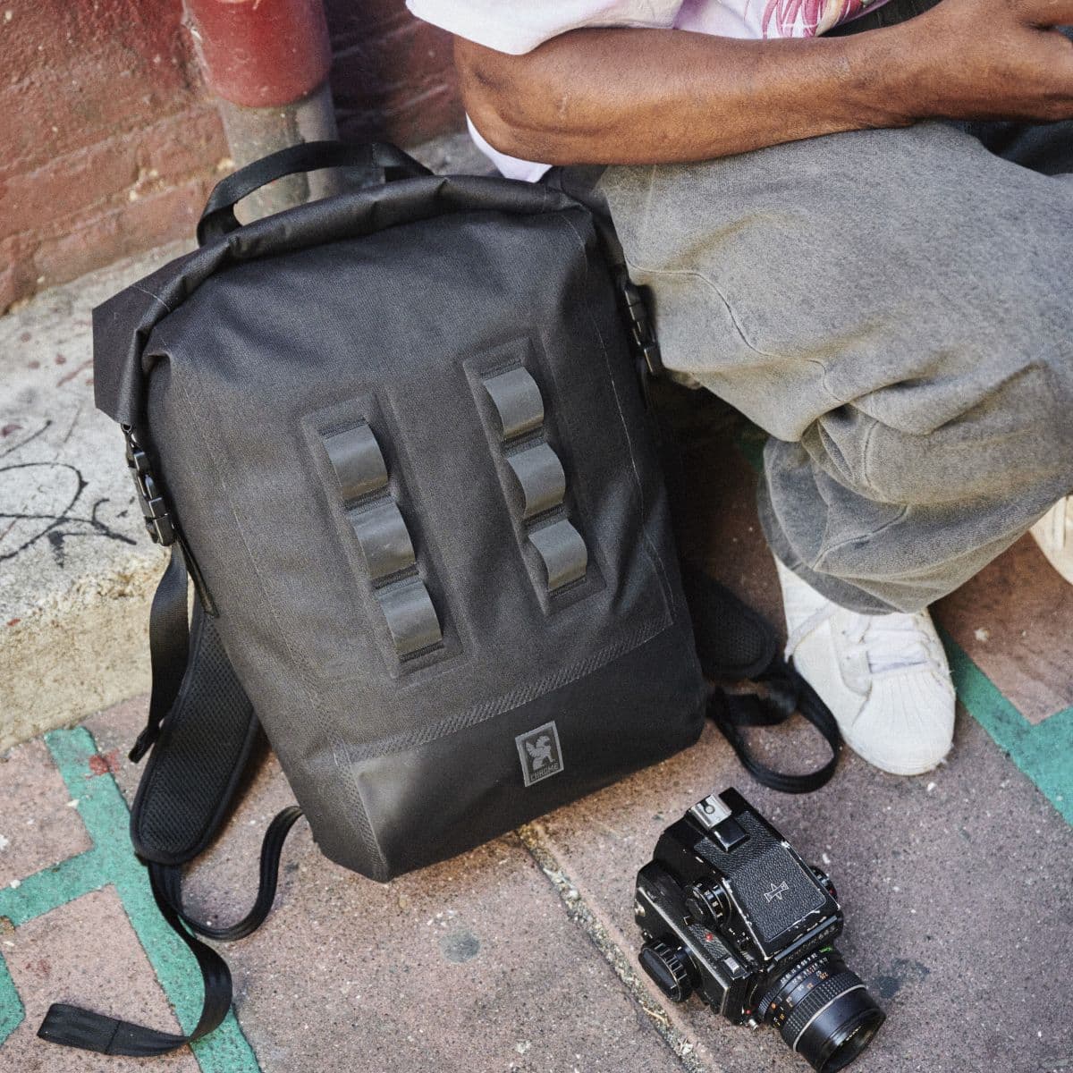 The Urban Ex 20L Pack on the sidewalk with a camera and a Man by it