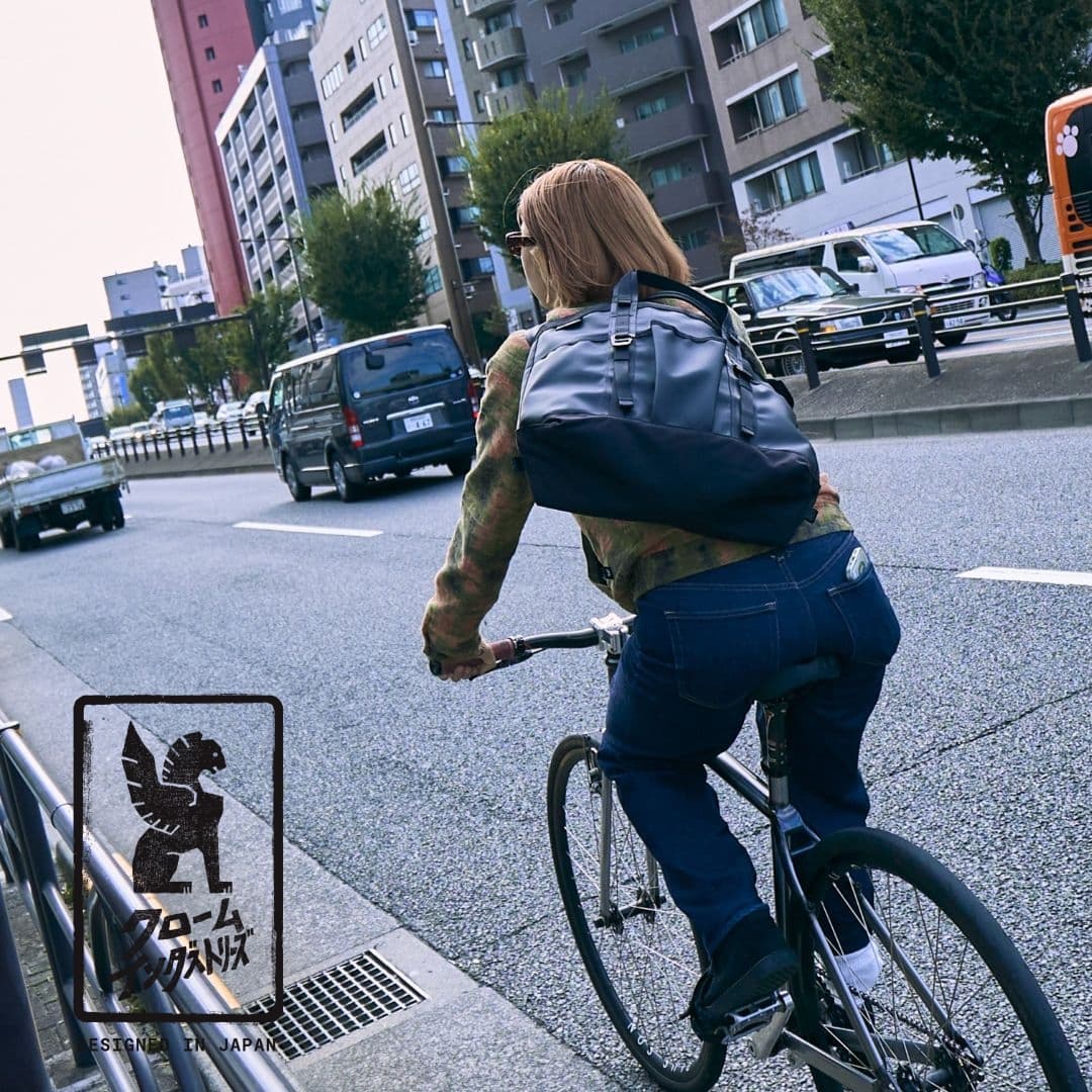 Person riding a bicycle on a city street in Tokyo wearing the Grocery Tote 28L.